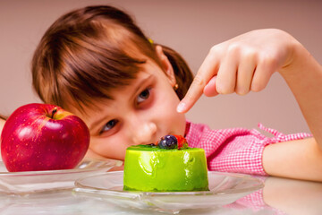Beautiful young girl eating cake, she prefer sweets than healthy food and fruit. Selective focus on cake.