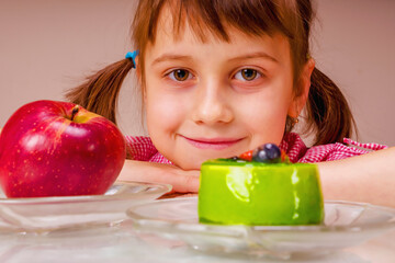 Portrait of young beautiful girl having hard choice between apple fruit and tasty cake.