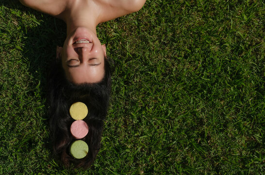 Young woman laying on the grass with natural eco friendly solid shampoo bar or conditioner on her hair. Zero waste and sustainable plastic free lifestyle