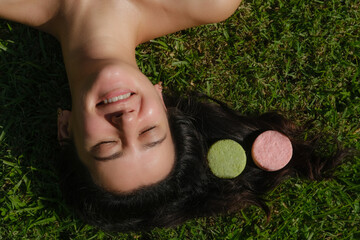 Young woman laying on the grass with natural eco friendly solid shampoo bar or conditioner on her...