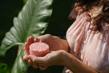 Young woman holding natural eco friendly solid shampoo bar, conditioner or soap. Zero waste and...