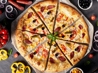 Pizza with hunting sausages, gherkins, mozzarella, olives and red sauce, top view