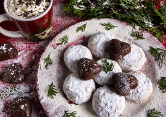 schokoladenkekse mit griehischen kourabbiedes, einer tasse kakao mit sahne, tannengrün und puderzucker
