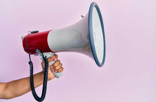Hand of hispanic man holding megaphone over isolated pink background.