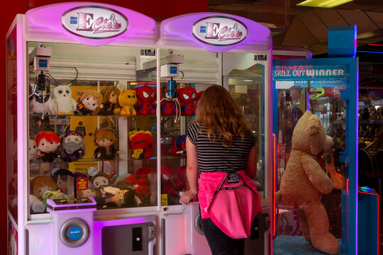 05/05/2019 Portsmouth, hampshire, UK  A young girl playing a claw crane grabber machine trying to win a teddy in an amusement arcade