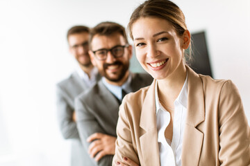 Smiling young business woman standing with group of corporate colleagues in a row together