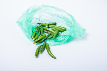 A green chili without a stalk in a green plastic bag. Isolated on white background