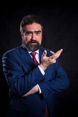 Mature businessman dressed in blue suit with red tie studio portrait.