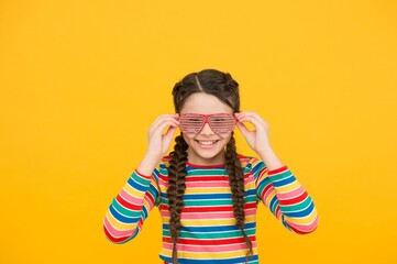 happy teen girl with stylish hairstyle. funny kid having fun. beauty in glamour glasses. childhood happiness. smiling child on yellow background. casual fashion accessory. party time