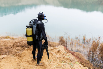A lifeguard in a wetsuit is preparing to dive into the pond. Search at the bottom of the pond.