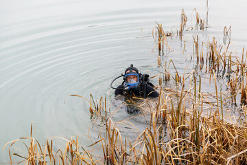 A lifeguard in a wetsuit is preparing to dive into the pond. Search at the bottom of the pond.