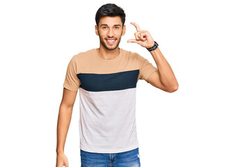 Young handsome man wearing casual clothes smiling and confident gesturing with hand doing small size sign with fingers looking and the camera. measure concept.