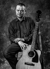 Mature musician plays acoustic guitar emotional studio portrait.