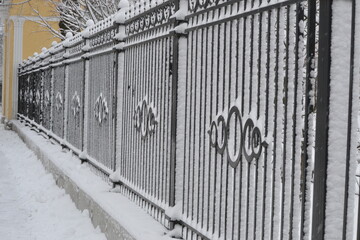 Fence winter snow. Sticking of snow on a metal fence in the background.