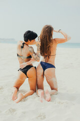 Fototapeta premium Two sexy caucasian women in bikini swimsuit on white sand beach. Sports, activity, rest on vacation