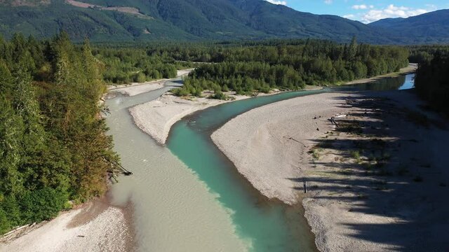 Picturesque Junction of Muddy and Turquoise Alpine River Water in a Green Summer Landscape of Washington State USA. Tilt Up Drone Aerial Shot