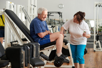 Obraz premium Unhappy senior man with severe pain in knee. Stressed elderly man injured leg at fitness club. Sport trauma concept.