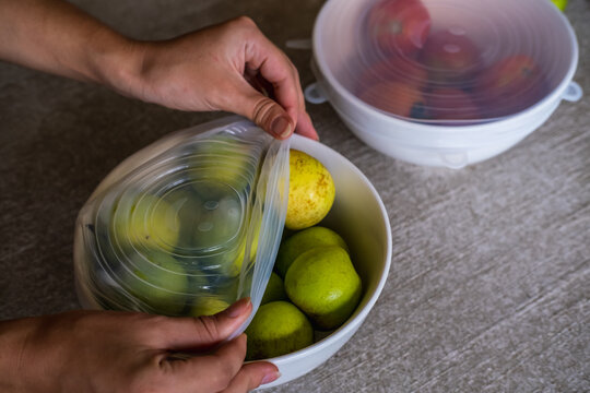 Close up of woman using environmentally safe round silicone stretch lids for fruits and vegetables storage. Reusable eco-friendly kitchen products. Zero waste sustainable plastic free lifestyle
