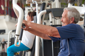 Older man training on press machine at gym club. Aged man training chest muscles using exercise...