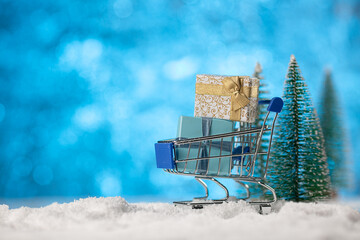 Christmas shopping concept. Shopping cart on snow full with christmas gift boxes
