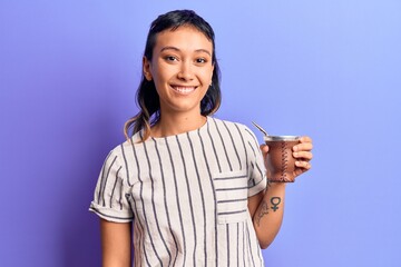 Young woman drinking mate infusion looking positive and happy standing and smiling with a confident...