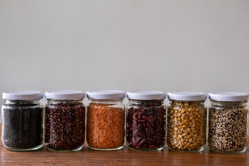 Different grains and beans in glass jars over white background. Eco-friendly organic bio bulk kitchen products. Zero waste and sustainable plastic free lifestyle