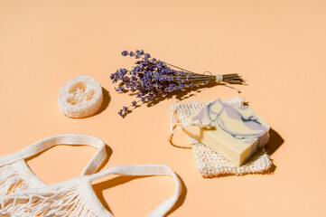 Natural handmade soap, loofah sponges with dried lavender and essential oil on cream color background. Zero waste concept