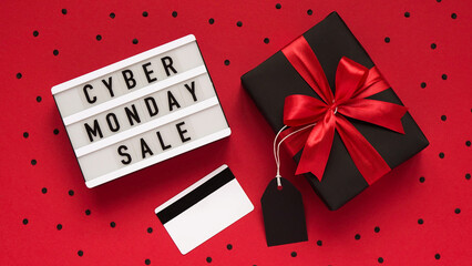 Fototapeta na wymiar Banner concept for Cyber monday celebration,lettering.White board with text CYBER MONDAY SALE,gift box with red bow,tag,credit card,confetti on red background,top view,flat lay,close-up