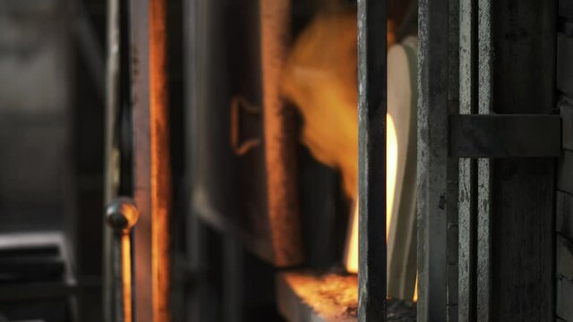 An old glass blowing furnace with hot flames as cool industrial fire background. A rustic fireplace burning gas to heat molten glass in a traditional factory in Murano, Venice. Slow-motion 4K.