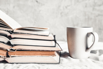 Naklejka premium Stack of opened books with a cup of coffee in bed