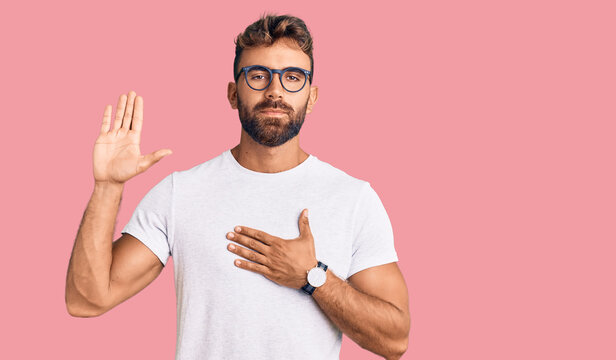 Young hispanic man wearing casual clothes and glasses swearing with hand on chest and open palm, making a loyalty promise oath