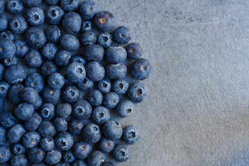 Half frame of freshly picked organic blueberries on grey stone texture. Winter harvest. Top view shot.