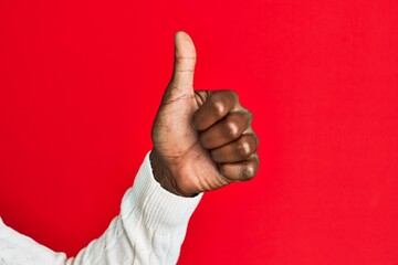 Arm and hand of african american black young man over red isolated background doing successful approval gesture with thumbs up, validation and positive symbol