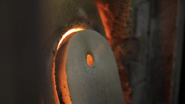 An old glass blowing furnace with hot flames leaking behind the stone covers. A rustic fireplace burning gas to heat molten glass in a traditional factory in Murano, Venice. Slow-motion background 4K.
