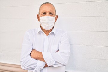 Senior man wearing medical mask standing at the city.