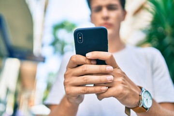 Young caucasian man with serious expression using smartphone at the city.