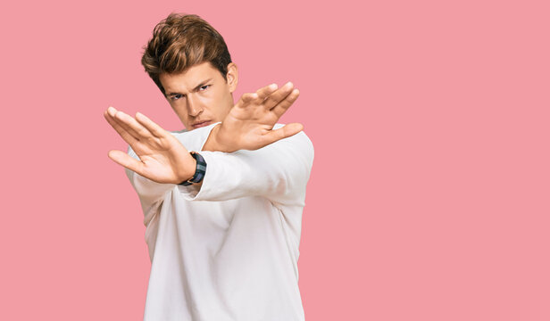 Handsome caucasian man wearing casual white sweater rejection expression crossing arms and palms doing negative sign, angry face