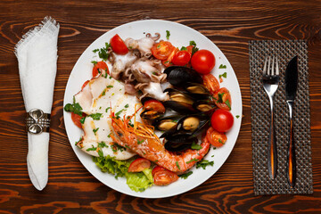 Assorted seafood on a plate on a dark wooden table.