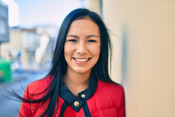 Fototapeta premium Young latin woman smiling happy leaning on the wall at the city.