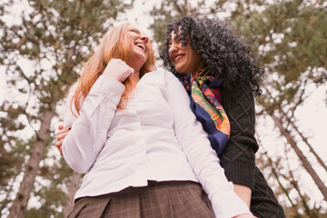 Fototapeta premium two girls with long hair having fun in the park, autumn outfit.Two pretty stylish women have fun 
