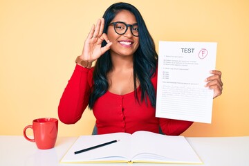 Beautiful latin young woman with long hair showing a failed exam doing ok sign with fingers, smiling friendly gesturing excellent symbol