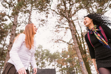 two girls with long hair having fun in the park, autumn outfit.Two pretty stylish women have fun 