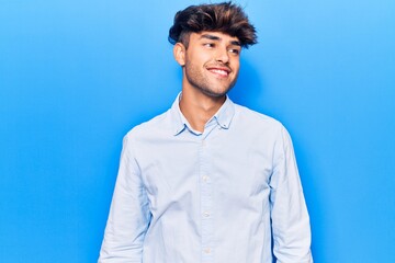 Young hispanic man wearing casual clothes looking to side, relax profile pose with natural face and confident smile.