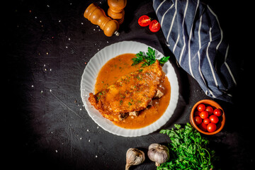 Potato pancakes with meat, vegetable, tomato and parsley on dark background