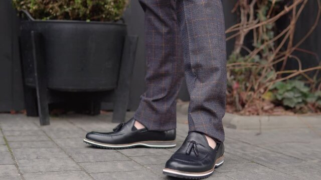 Close-up of a man's feet in brown pants and new black shoes from the new collection