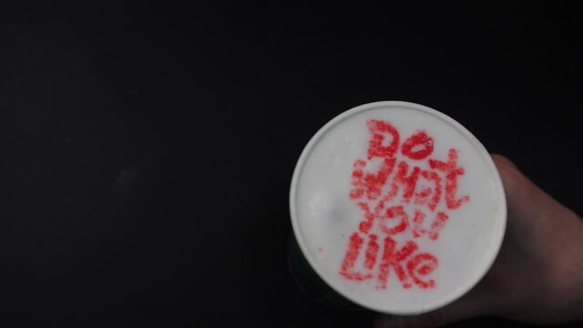 Person takes fresh coffee with red words Do What you Like