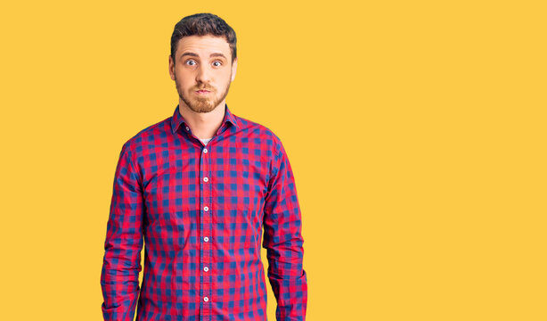 Handsome young man with bear wearing casual shirt puffing cheeks with funny face. mouth inflated with air, crazy expression.