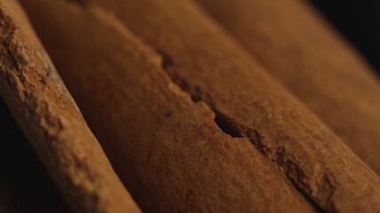 Cinnamon sticks on a dark background.  Spicy cinnamon seasoning for baked goods, fruit desserts, puddings and drinks. Extreme close-up, macro view