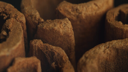 Cinnamon sticks on a dark background.  Spicy cinnamon seasoning for baked goods, fruit desserts, puddings and drinks. Extreme close-up, macro view