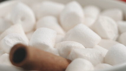 Fototapeta na wymiar Many delicious sweet white marshmallows close-up. Swim on cocoa. Macro shooting. Hot cocoa with marshmallows, cinnamon in a white mug. Soft focus, depth of field